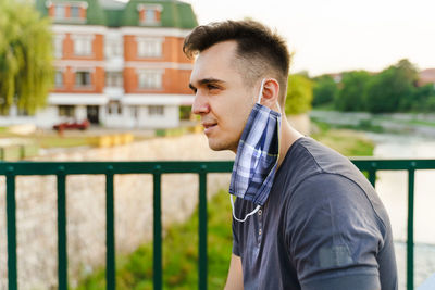 Portrait of young man standing against railing