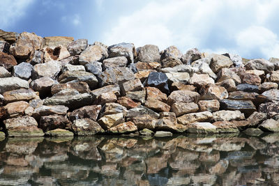 Stack of rocks in water against sky