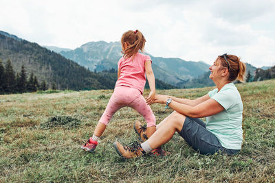 Little girl playing with her mother on grass enjoying summer day. happy family playing in the field