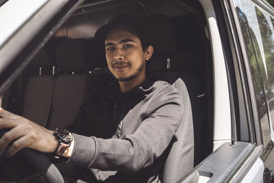 Portrait of confident delivery man driving truck