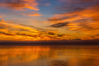 Scenic view of sea against dramatic sky during sunset