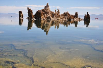 Reflection of rocks in water against sky