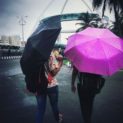 Rear view of woman with umbrella standing on wet street