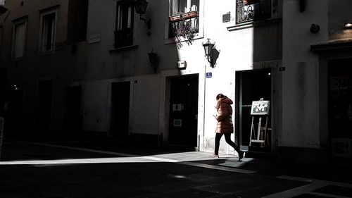 Woman walking on street against buildings in city