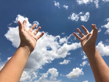 Low angle view of person hands praying against sky