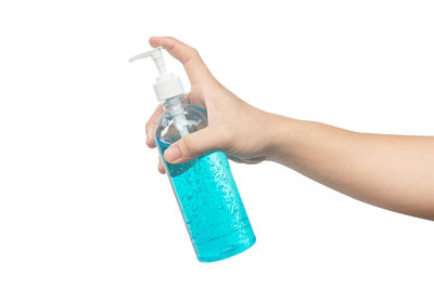 Close-up of hand holding bottle against white background