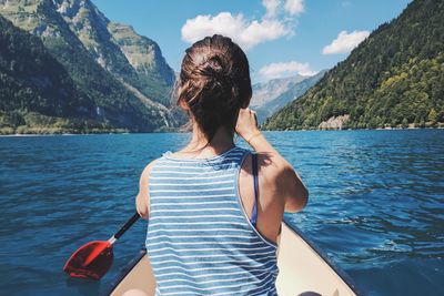 Rear view of woman on shore against mountains