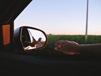 Close-up of hand holding car against sky