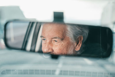 Reflection of smiling senior man sitting in car