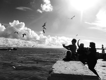 Tourists enjoying on beach against sky