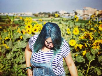 Beautiful young woman standing against yellow plants