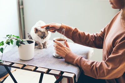 Midsection of woman holding coffee mug on table