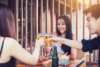 Friends toasting drinks while sitting in restaurant