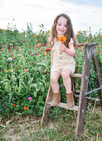 Portrait of young girl sitting on step ladder in a flower field