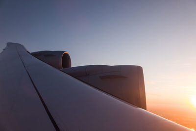 Airplane wing against sky during sunset