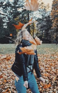 Full length of woman standing by tree during autumn