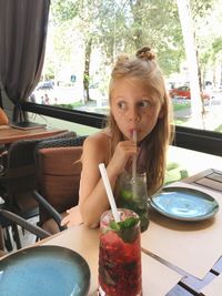 Portrait of girl drinking glasses on table at restaurant
