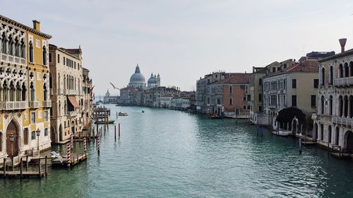 Canal amidst buildings in city against sky