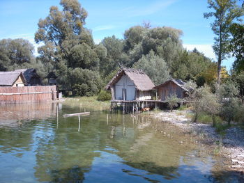 Houses by lake against sky