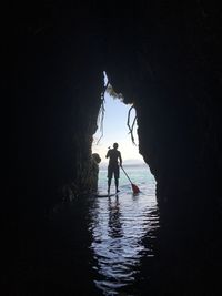 Man on paddle board in sea seen through arch