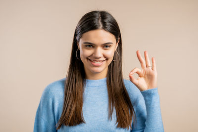 Portrait of a smiling young woman against gray background