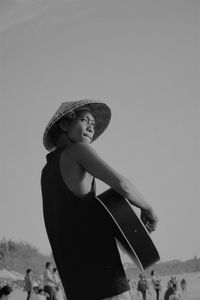 Low section of woman wearing hat standing against sky