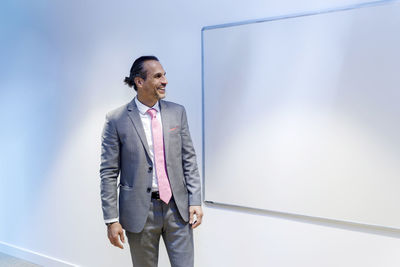 Happy businessman looking at whiteboard in conference room