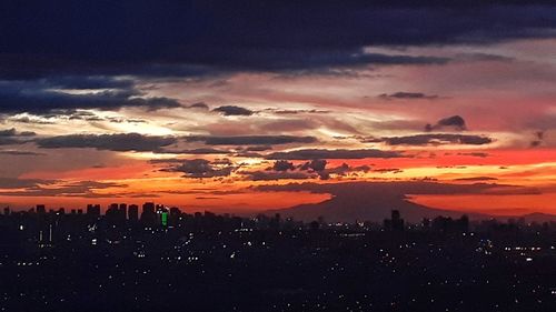 Scenic view of silhouette city against romantic sky at sunset