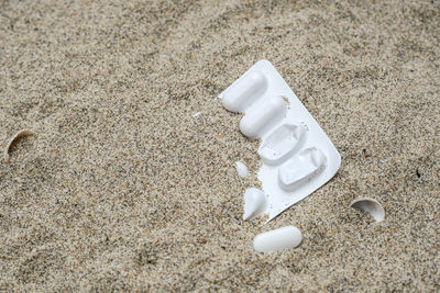 Plastic medicine blister container discarded pollution on sandy sea coast ,cilento