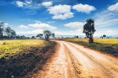 Dirt road against blue sky on sunny day