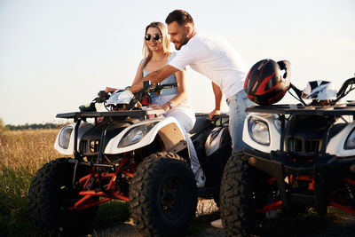 Side view of man riding motorcycle on field against clear sky