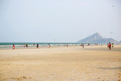 People enjoying at beach against sky