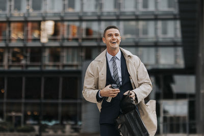 Happy businessman laughing while walking in front of office building