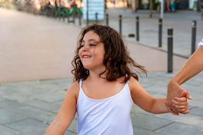 Midsection of woman with arms raised against blurred background