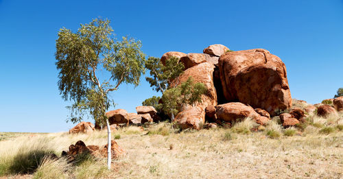 Rock formations on landscape against clear blue sky