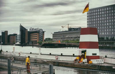 Buildings by river in city against sky
