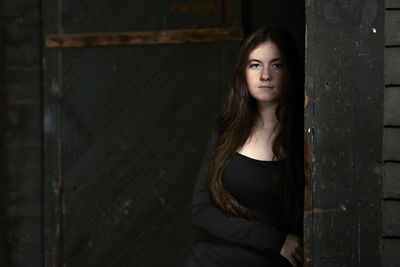 Portrait of young woman standing against wall