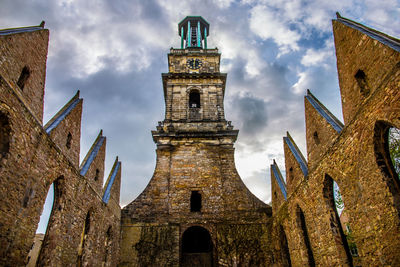 Low angle view of clock tower against cloudy sky