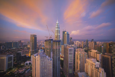 Aerial view of city lit up against cloudy sky