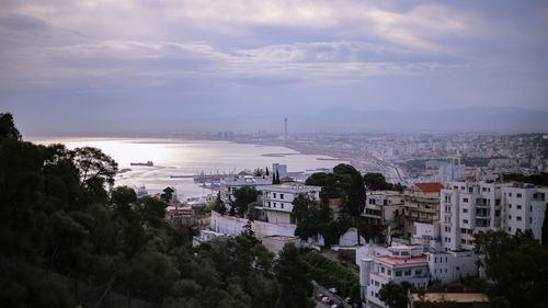 High angle view of city by sea against sky