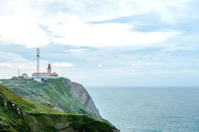 View of lighthouse on sea against cloudy sky