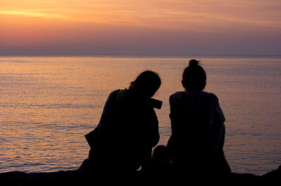 Silhouette people against sea during sunset