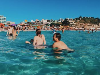 People enjoying in swimming pool against sea