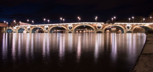 Illuminated bridge over river at night