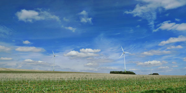 Wind turbines on field against sky