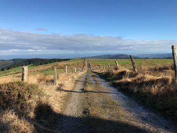 Road amidst field against sky