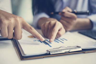 Midsection of man holding paper with text on table