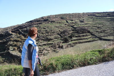 Rear view of woman standing on field against clear sky