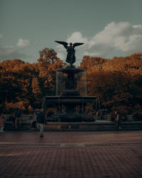 Statue by trees against sky during autumn