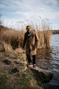 Full length of man standing in lake against sky during winter